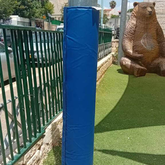 מגן עמודים מותקן על עמוד במגרש משחקים כדי להגן על הילדים מפני פציעות.